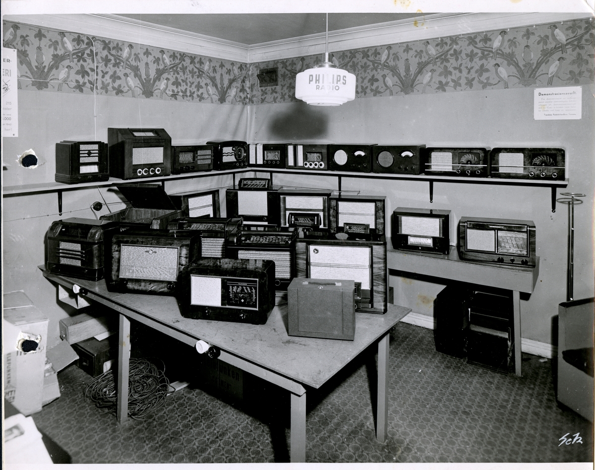 Fra familiealbum. Fotografi av radioavdelingen hos Olaf T. Ranum A/S. På taklampen over bordet står det Philips radio.
