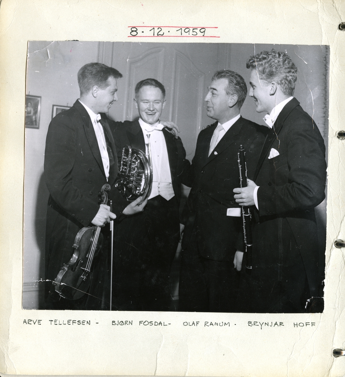 Gruppefotografi av tre musikere som står rundt Olaf Ranum. Fra venstre Arve Tellefsen på fiolin, Bjørn Fosdal på horn, Olaf Ranum og Brynjar Hoff på klarinett. Samlet i anledning butikkens 60-års jubileum.
08.12.1959.
