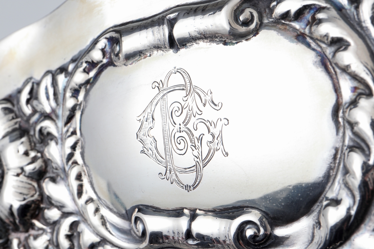 Fat av silver.
Ovalt prydnadsfat, med pressad dekor i hög relief på brättet, bestående av blommor och bladornament. Brättet är försett med två bekransade ramar, i den övre kanten är ett graverat monogram: "G B". I den undre kanten står: "19 22/12 35". På fatets baksida finns följande text: "Till Gunnar Borner på 50-årsdagen från kollegor i Kronobergs län". 
Stämplar på brättets undersida.

Inskrivet i huvudbok 1962