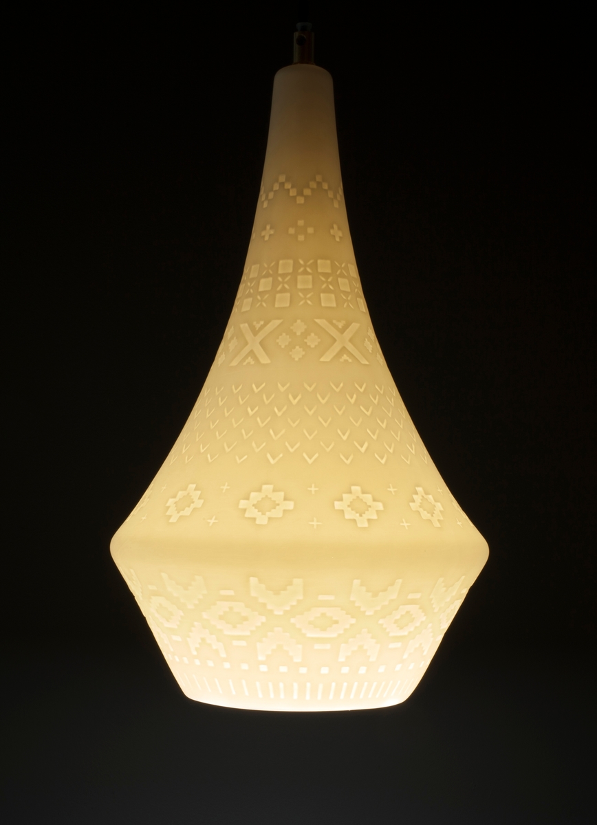 Lampens sandblåste mønster består av "strikkemasker", altså pikselerte punkter (kvadrater, "lus") som skal illudere mønstre fra strikkede klesplagg. En omsirklende rekke av åttebladsroser er det ornamentet som preger mønsteret mest, mens border og punkter er med og skaper assosiasjonene til plagg som gensere og votter. De tekstile referansene gir lampen en lun karakter, noe som forsterkes når lyset i den tennes.
