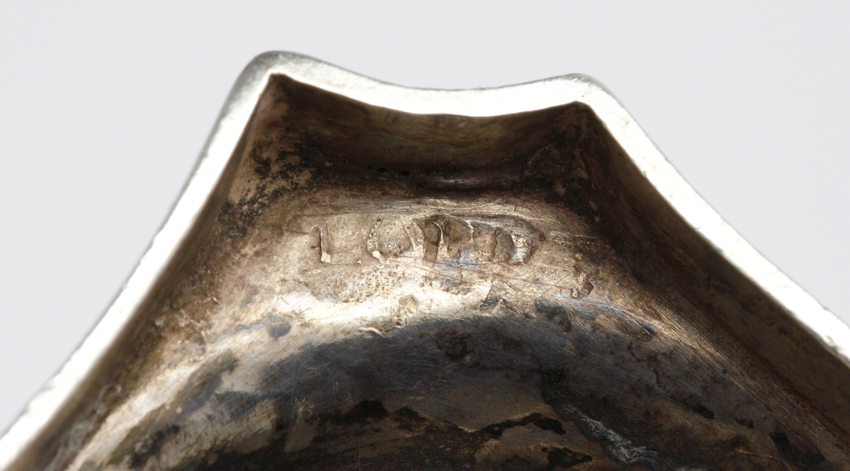 S.k. supkalk av silver, med ben och fot. 
Graverat mönster på skålens kant och på foten. Invändigt är cuppan förgylld. Foten är åttkantig. 
Stämplar (deformerade, svårtydda) i botten. 

Inskrivet i huvudkatalogen 1963.