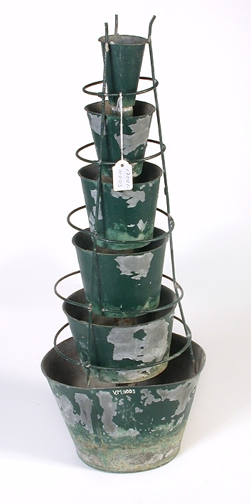 Bestående av sex över varandra sittande runda skålar av grönmålad plåt, den nedersta störst, den översta minst.