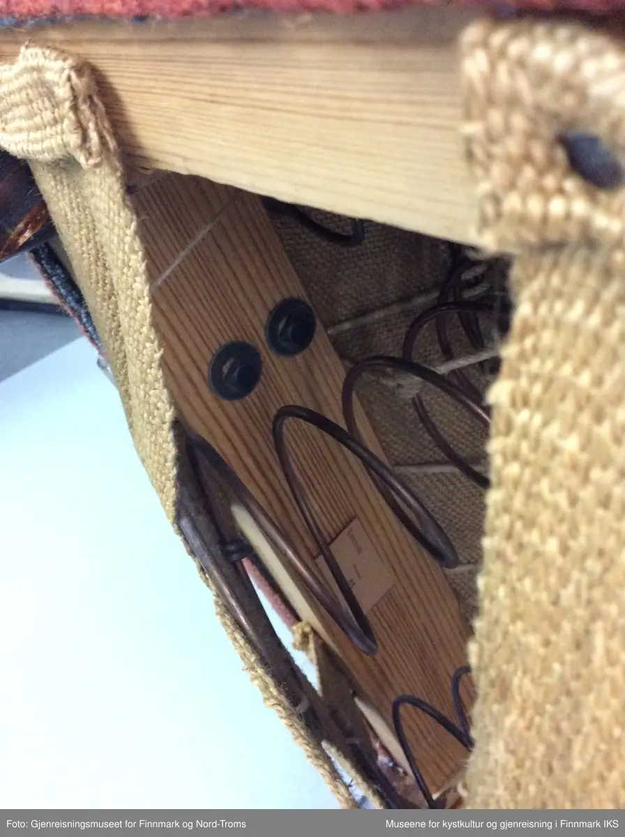 Sofaen er en treseter med polstring i rygg og sete. Den er trukket med rødt stoff og har naturfarget kantbånd som rammer inn hele møbelet. Kantbåndet deler også inn både rygg- og sete, i tre partier. Armlenene er buet og er festet i nedre delen av ryggen og i ramma.
Benene er firkantede. Ramma har ei tverrstøtte i midten. Det er festet striper av strie med spiker på undersiden. I striene er det festet sylinderfjærer som på oversiden er festet med hyssing til hverandre. På fjærene ligger et lag med striestoff og oppå der igjen er det et fyllmateriale. Øverst kommer trekkstoffet som er festet på undersiden av ramma. 