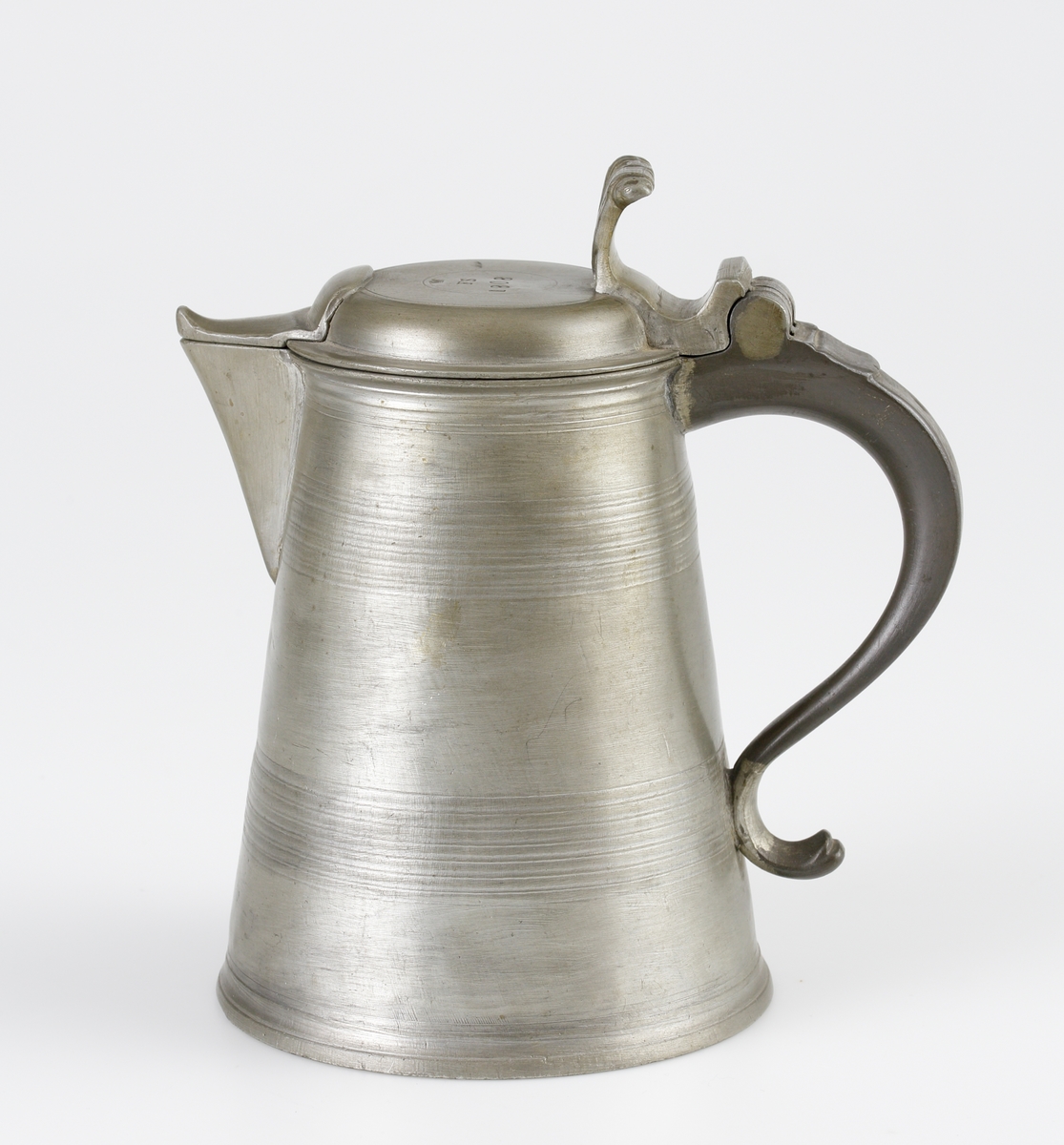 Stop av tenn.
Konisk, bandad modell. Svängd hänkel och ornerat, svängt tumgrepp. Svängd snås. 
Ovanpå locket är stämplat en krona, ägarinitialer: "FS" och årtalet 1808. 

Inskrivet i huvudbok 1982.