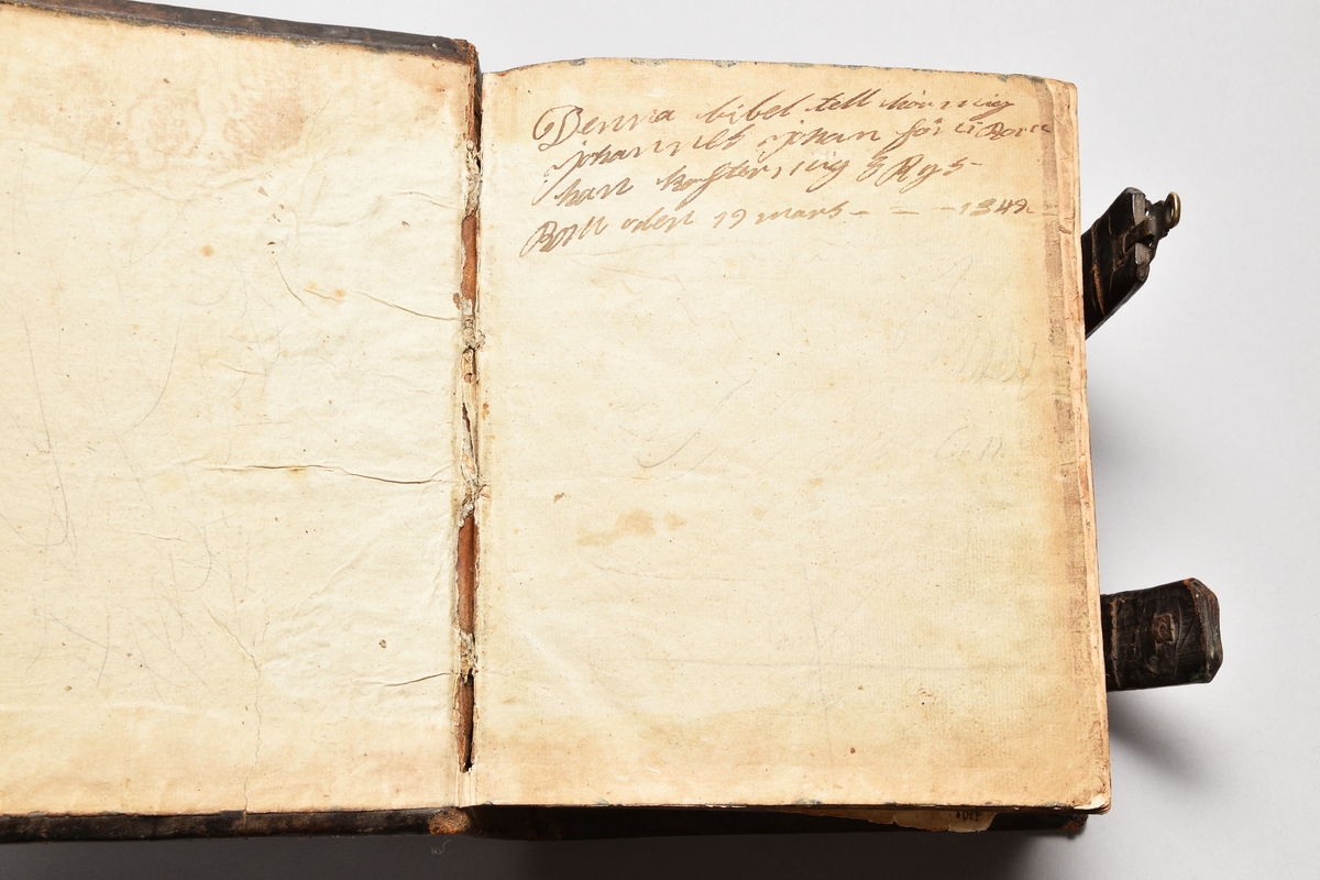 Bibel med band av skinn, rygg med fyra upphöjda bind. Två bokspännen av skinn och mässingsknäppen.