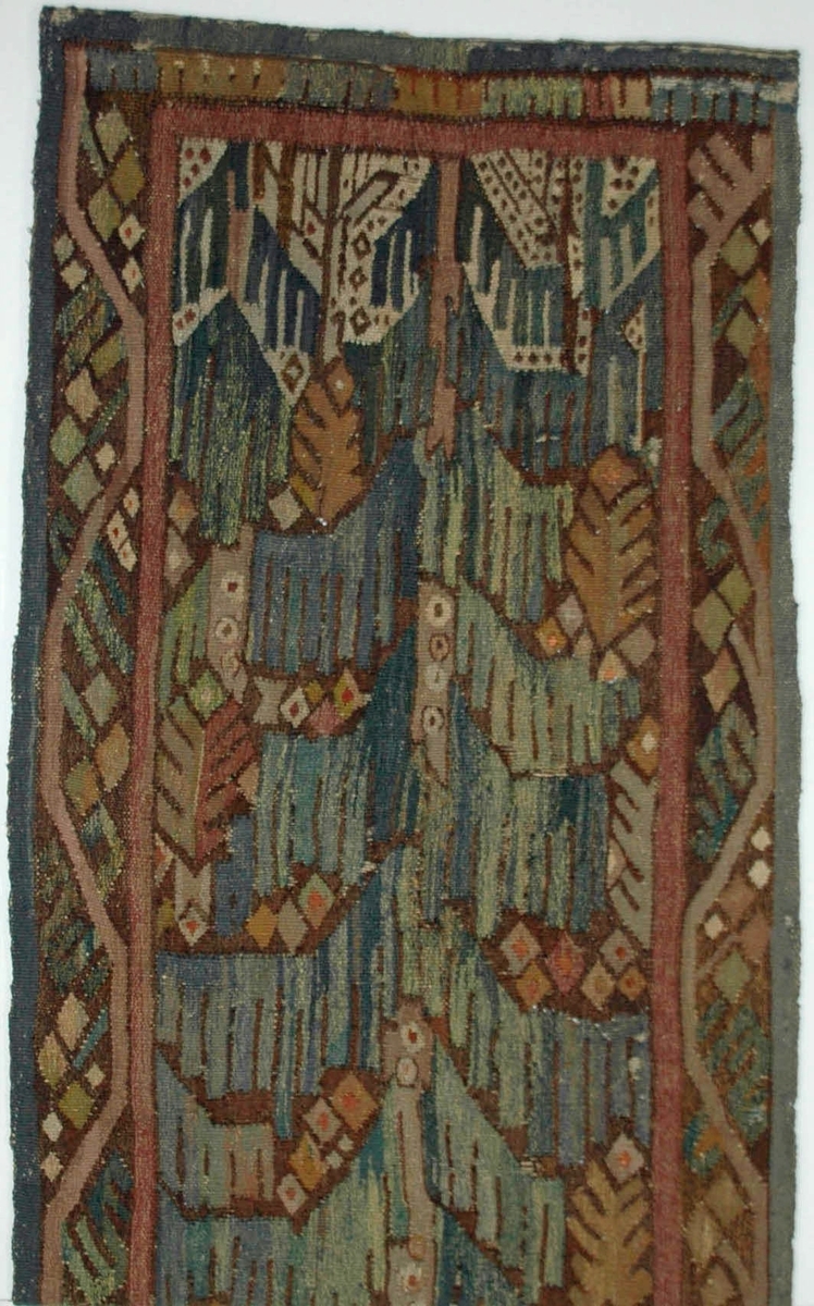 Väv/gobelin "Granen vid badstället" komponerad av Märta Måås-Fjetterström. Delvis nött. Denna nästan 2 meter höga gobeläng komponerade Märta Måås-Fjetterström år 1918 som gåva till sin vän och arbetsgivare vid Vittsjö vävskola Lilli Zickerman på hennes 60-årsdag. Med stor sannolikhet är den utförd av Märta Måås-Fjetterström själv. Till föremålet finns även en skiss i akvarell, GM42723.