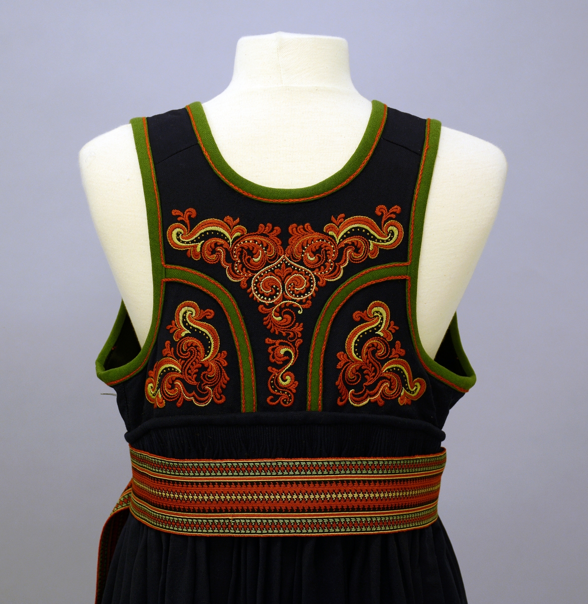 Øst-Telemarksbunad, sydd av Anne Bamle i 1926.TGM-BM.1977:381.A-E
C. Belte. Brikkevevd belte, festet med tråklesting til stakken 1 cm nedenfor baugen. Bredde: 6,5 cm, lengde: 132 cm, hvorav 14 cm frynser som dannes av renningen. Vevd med 63 brikker i mykt 4-tråds ullgarn i farvene rustrødt, gult, grønt og sort med den den rustrøde som dominerende i  midtpartiet og grønne striper på sidene. 1 trykkapp og 3 hekter holder beltet sammen på venstre side 12 cm fra midten, enden med frynsene faller fritt ned.