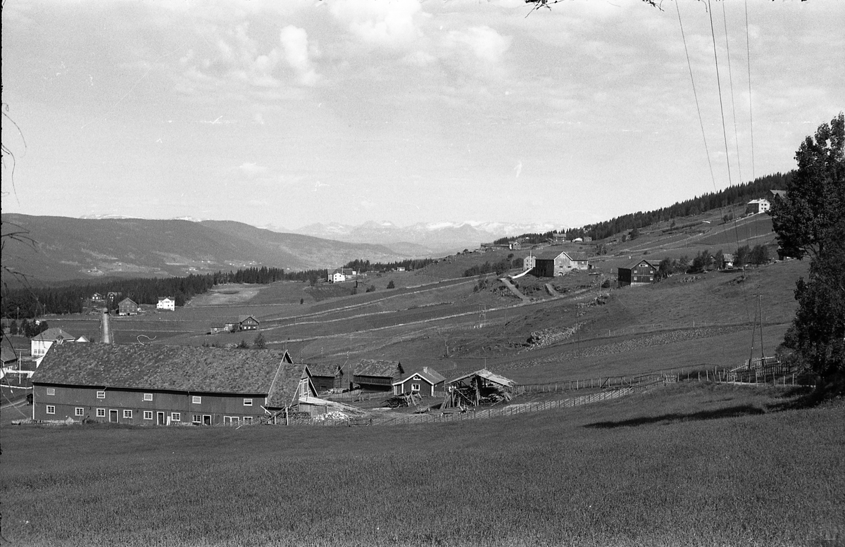 Landskapsbilde fra Skrautvål i Nord-Aurdal. Gården i forgrunnen har navnet Skrautvål. Den hvite bygningen bak låven er Skrautvål skole. Fjellene i horisonten er i Jotunheimen.