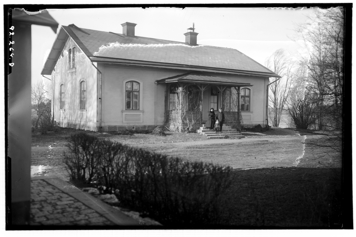 Ervalla stinsbostad. 
En kvinna, en man och ett barn på trappan. Mannen bär uniform.