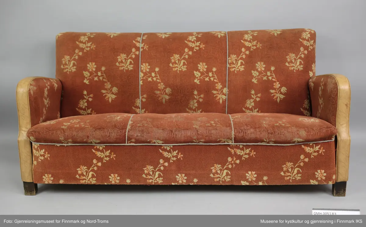 Sofaen er en treseter der rygg og setet er avgrenset med tvinnede pyntebånd i grått. Rygg, sete og armlener er polstret og trekt med et stoff som har rødbrun bunnfarge og et lysebrunt blomstermønster. Trekket er spikret til ramma på undersiden og på armlenen på utsiden. På kanten er armlenene trekt med lysebrun kunstskinn. På undersiden er sofaen lukket med plater, slik at polstringa ikke er tilgjengelig. Det er likevel synlig at sofaen består av en ramme med to tverrforbindelser. Dette er et inngrep som mest sannsynlig er gjort for å få støttet opp under sylinderfjærene. 