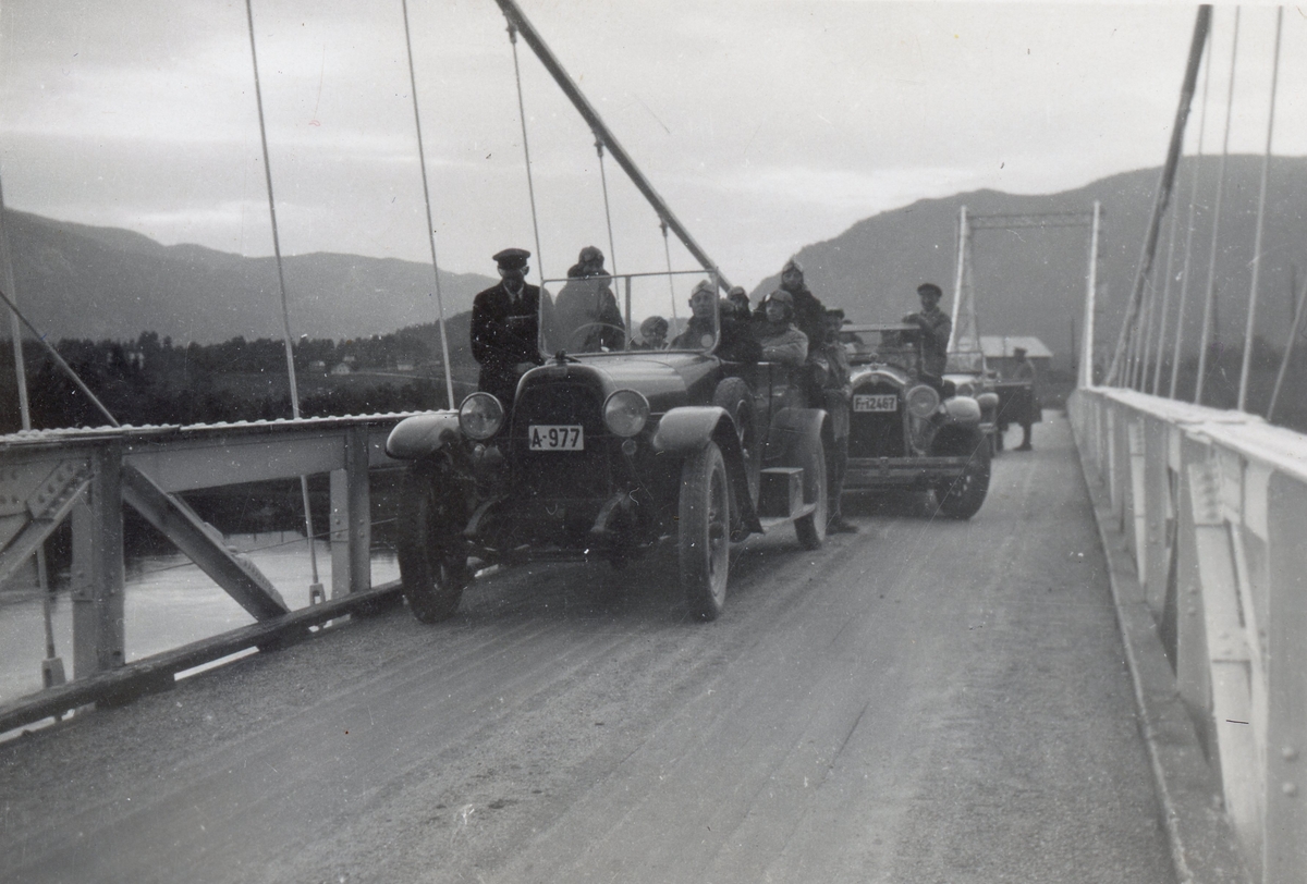 Knut Granheim og Torleiv Smøttebråten køyrer følgjet til kong Alfonso av Spania i 1930 frå Lærdal til Oslo.  Torleiv Smøttebråten står i bilen sin reg nr. F-12467. Knut Granheim står ved sida av bilen sin reg nr.F.12483. Biletet er tatt på Gulsvik bru.
Den andre bilen en nash reg nr. A-977 er ukjent.