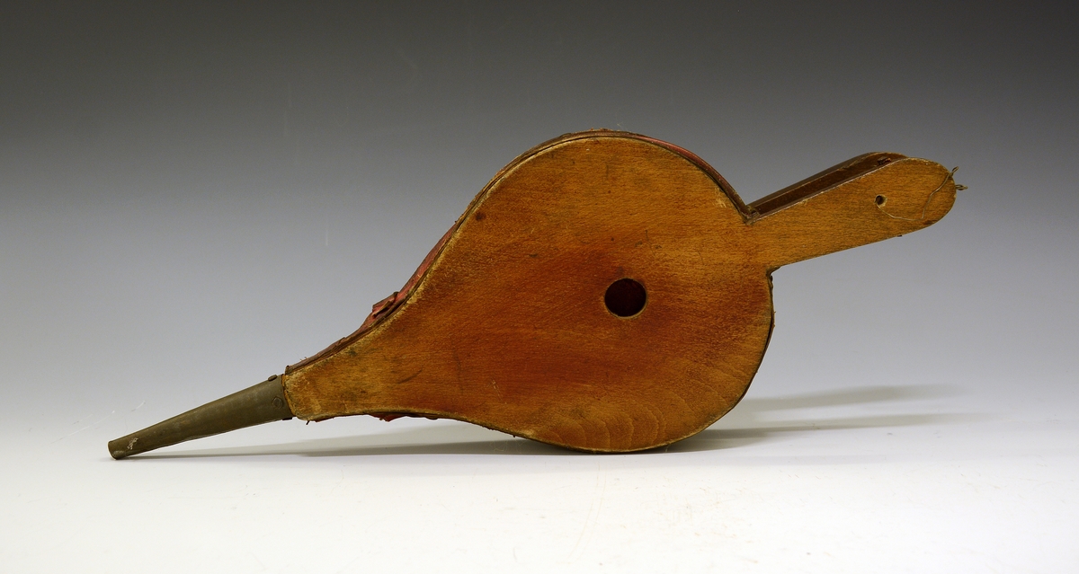 Ovnsbelg. Fra protokoll: Omnsbelg (omspustar)  i uvand blekkpipe. pæreforma bokvedbynir, raudt saffiand skinn, nagla med salmakarstiftur. Lengd med skaft og pipe 38,5 cm.