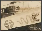 Bilden visar en målad patriarkalkors och en orm med vingar som utsmyckning på ett flygplan. Patriarkalkors eller Lothringenkors var sedan 1912 del av flaggan för den dåvarande tyskt delstat Elsass-Lothringen.