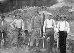 Repro: Seks anleggsarbeidere med spader og trillebår i Seteranlegget på Maihaugen.