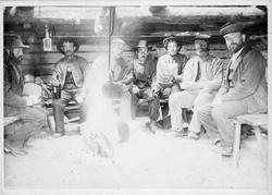 Repro: Sju lågåsildfiskere i  Knuvelbua på Maihaugen.