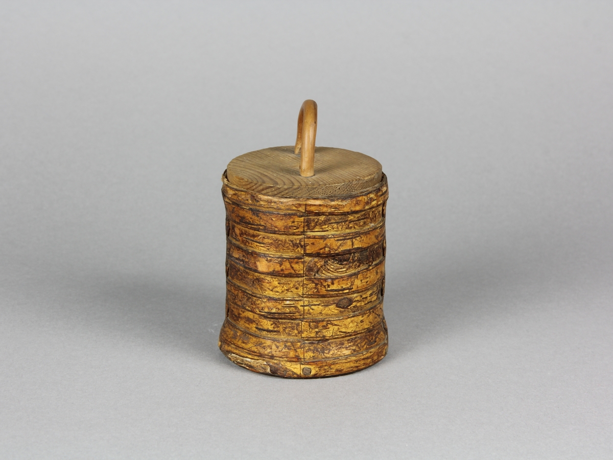 Snusburk, cylinderformad av hel näver med lock och botten av furu. Nävern ornerad i rut- och prickmönster. Näverändarna fästa genom att de tampats och flätats ihop. På locket tvärgrepe av enträ som kilats fast från undersidan. Snusrester i botten.