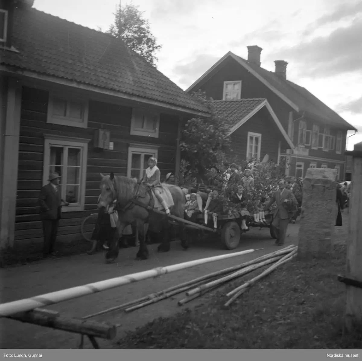 Motiv: (ingen anteckning) ;
En kvinna och två män spelar boccia, porträtt av en kvinna i folkdräkt, en folksamling står vid en gärsgård, tre män i folkdräkt rider på hästar framför män som spelar fiol och kvinnor i folkdräkt som går på en väg "Midsommartåget till Tibble", en kvinna i folkdräkt rider på en häst som drar en vagn med barn, kvinnor och män pryder en midsommarstång med lövade ringar.dju