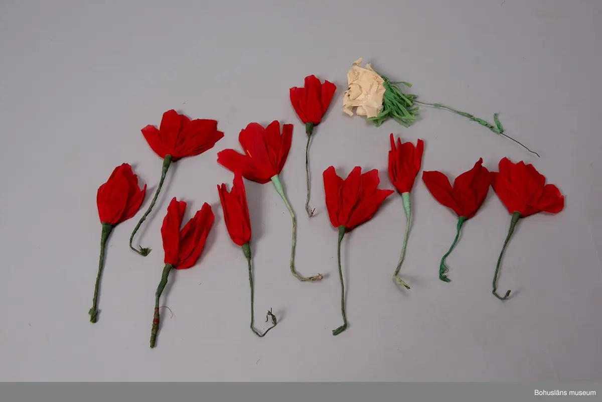 Låda av brun papp. På locket påklistrad,delvis bortsliten etikett med text: "Herman Radyn Uddevalla". Lådan innehåller: 19 st. julgransljushållare, glitter i silver, glitterband i guld, 7 st. julgranskarameller av papper, 1 toppstjärna, 12 st. hjärtan av papper i olika färger, 6 st. små glasbollar i sytråd, svenska flaggor i tråd, 12 st. svenska flaggor med järntråd,