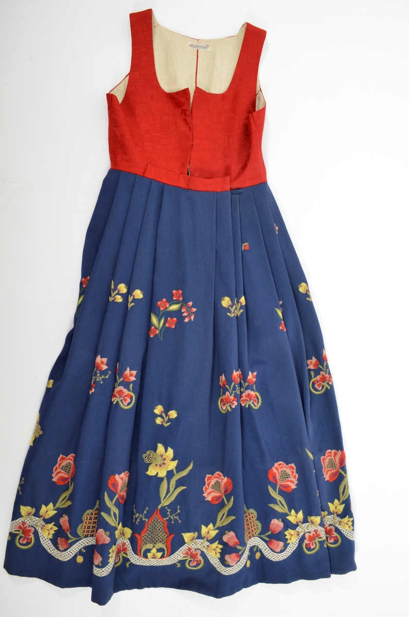 Grafferbunad med raudt damaskvove ulltøy i livet, og blått toskaftvove ulltøy i stakken. A. Livet har opning framme festa saman med tre hekter og krokar. Saum midt bak, og med to svinga ryggsaumar. Fóra med ubleikt halvlin.
Stakk i toskaft-vove ulltøy, brodert med ullgarn i forskjellige fargar. Rosemotiv. Den er foldelagt. Brei skonnering av svart bomulltøy i  nedrekanten.
B. Jakke i blått toskaftvove ulltøy. Opning midt framme med tre hekter og krokar til lukking. Eit snitt på kvar side. Erme er foldelagt oppå skuldera og nede ved ermekragen. 
C. Lue, pullue, i same tøy og broderi som stakken. Fóra med ubleikt halvlin. I nedrekant av pullen løpegang med rynka strikk. 
D. Lomme i same tøy og broderi som stakken. Sølvforgylt lommelås.