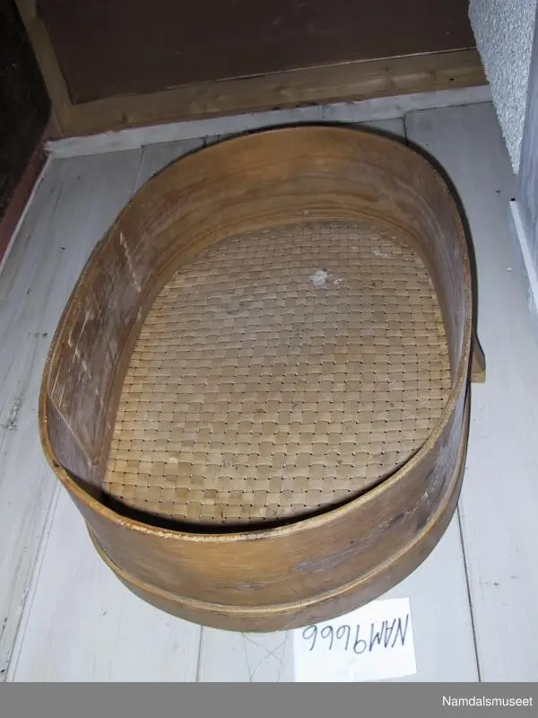 Form: Oval, sveipet sammen, sponfletting i topp (bunn?). Her et for feste på sidene.
