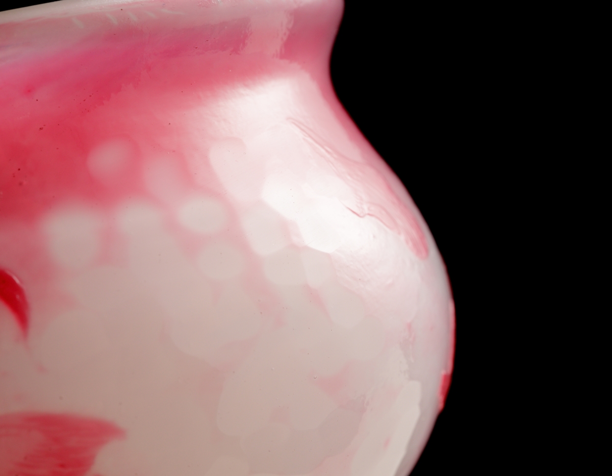 Skål med opaliserande vitt glas och mörkrosa överfång. Dekor av svagt stiliserad kvist med äppelblom. Gröna fläckar på insidan bakom bladen.