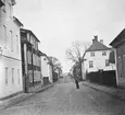 Suddig men unik vy från Linköping. Nygatan sedd mot öster. Lite bortom mannen på gatan löper Läroverksgatan från vänster och Djurgårdsgatan från höger. Det vita huset till höger ägdes från 1873 av fotografen Maria Tesch. I hennes ateljé på gården har tusentals linköpingsbor låtit fotografera sig. 1860-tal.