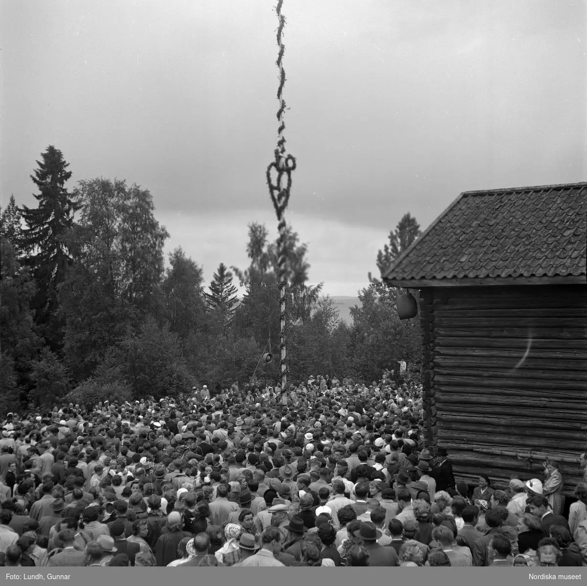 Motiv: (ingen anteckning) ;
En folksamling står kring en midsommarstång, en folksamling vid ett hus, en kyrkbåt ros av kvinnor och män i folkdräkt, en folksamling står vid en brygga med en kyrkbåt.