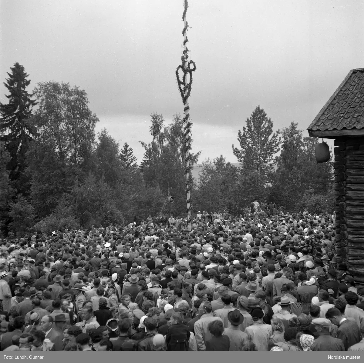 Motiv: (ingen anteckning) ;
En folksamling står kring en midsommarstång, en folksamling vid ett hus, en kyrkbåt ros av kvinnor och män i folkdräkt, en folksamling står vid en brygga med en kyrkbåt.