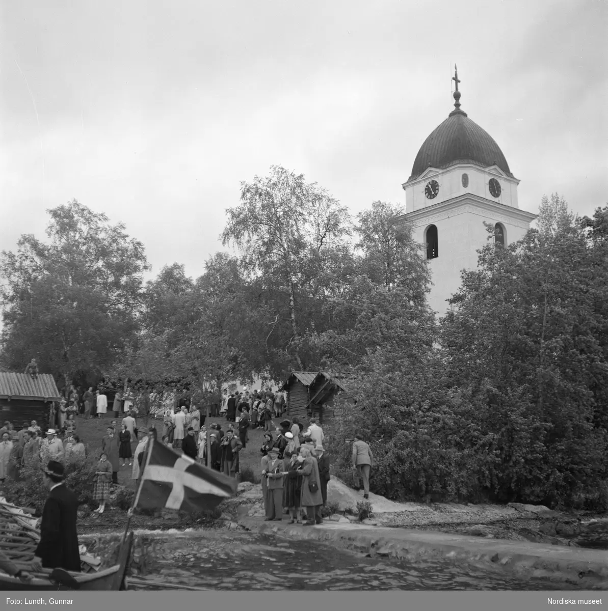 Motiv: (ingen anteckning) ;
En man i folkdräkt står i en kyrkbåt, en folksamling står vid Rättviks kyrka, utsikt genom ett fönster med människor som går på en väg, interiör av en kyrka med besökare, en person tar upp kollekt.