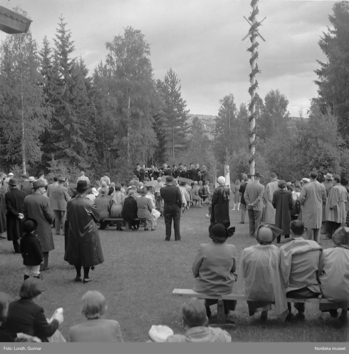 Motiv: (ingen anteckning) ;
Två män i folkdräkt håller fioler, en man i en talarstol talar till en folksamling, ett barn sitter på trapan till en talarstol, en folksamling vid en midsommarstång, porträtt av två varav ett i folkdräkt, kvinnor och män i folkdräkt dansar vid en midsommarstång.
