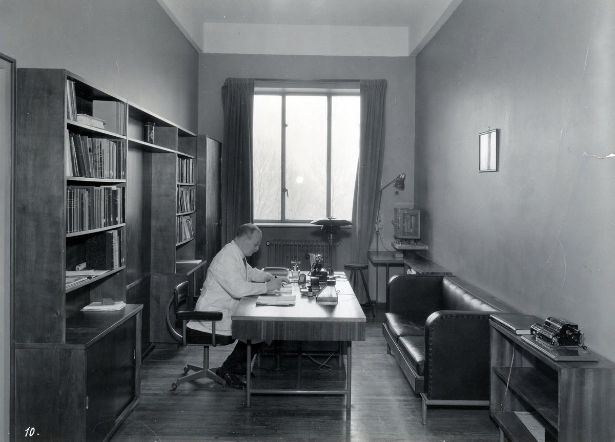 4 fotos av Farmasøytisk Institutt, Oslo: Interiør og eksteriør.
Professor Axel Jermstad på sitt kontor.
Modell av universitetsanlegget.
Trappeoppgang
Møterom