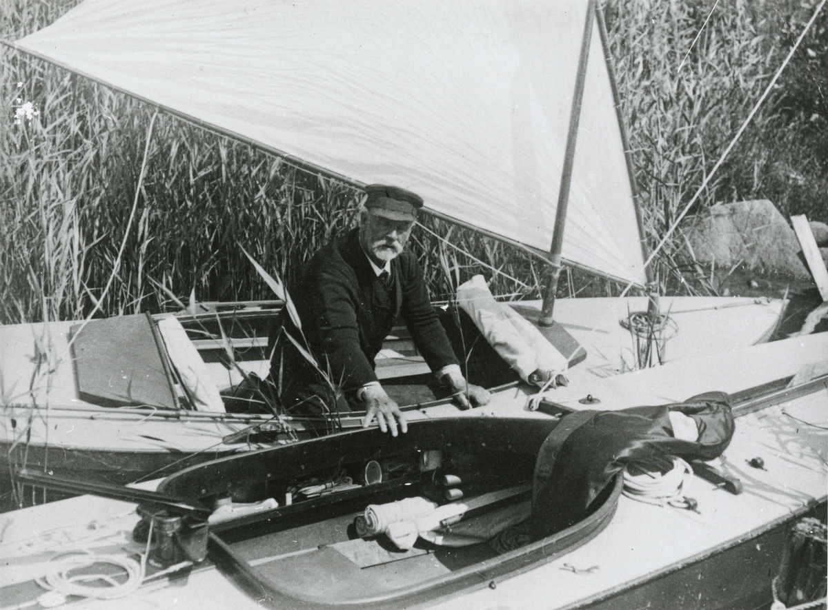 "Kommendör Carl Smith fotograferad av Erik 'Boa' Boström vid ett av sina besök hos gamle kommendören. Närmast Boa:s barlastade 3B-are 'VIKING'. Foto antagligen 1915, då Boa besökte Smith. Kommendörens båt kan vara kanotyachten 'RARA', som ritades för en klass där längd och bredd i vattenlinjen inte fick överstiga 6.50 m. 'RARA' deltog en gång i en kappsegling mot betydligt större båtar, och vann då 1:a priset."(uppgiftslämnare L. Reinholdson)