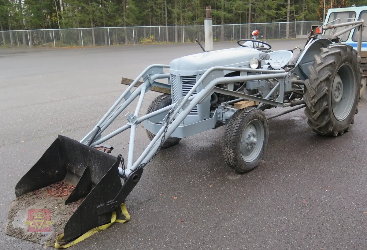 Ferguson TEA20. Grå traktor med lasteapparat foran og graveaggregat bak. Motoren er en 4-sylindret bensinmotor fra Standard Motor Company.