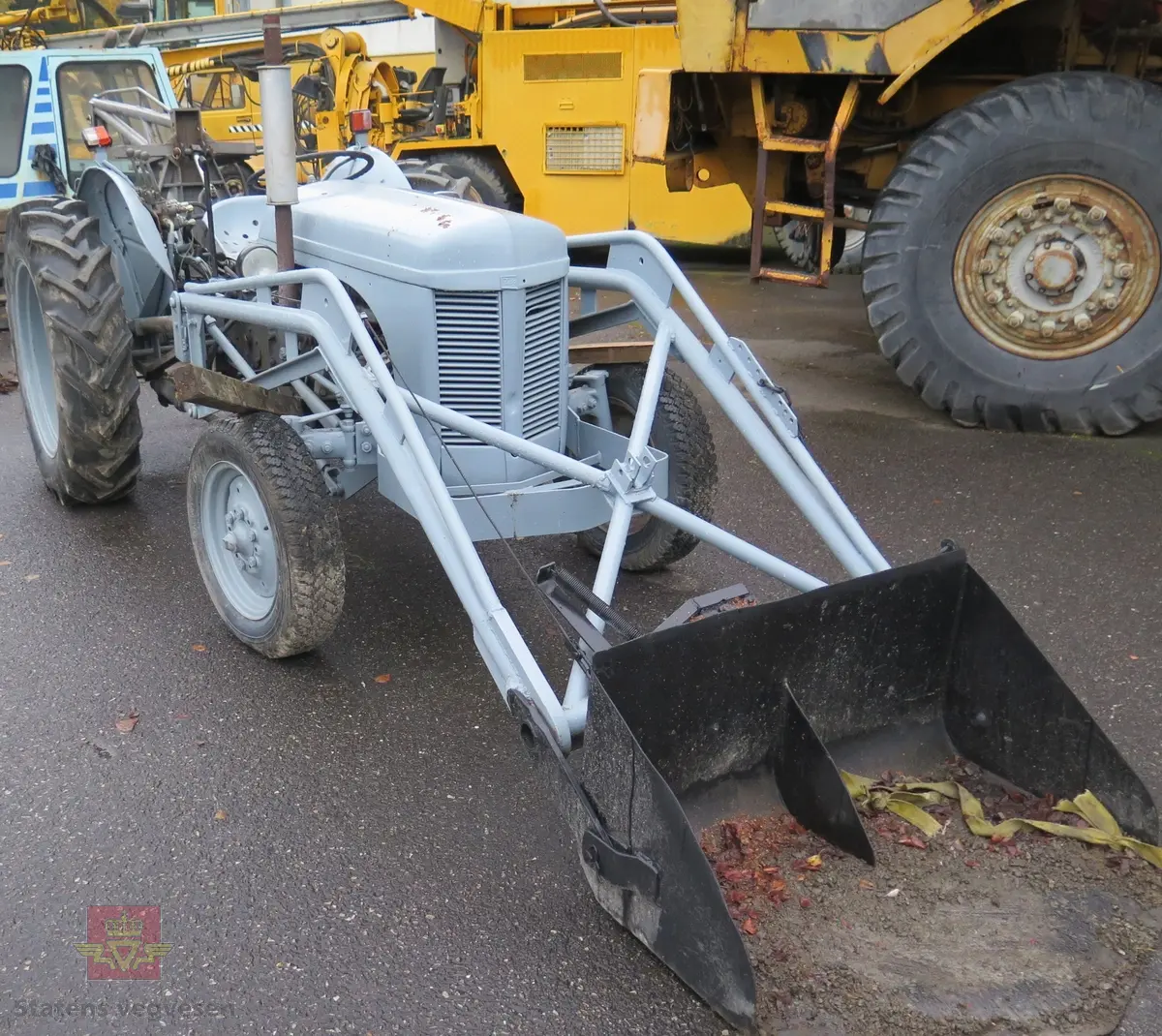 Ferguson TEA20. Grå traktor med lasteapparat foran og graveaggregat bak. Motoren er en 4-sylindret bensinmotor fra Standard Motor Company.
