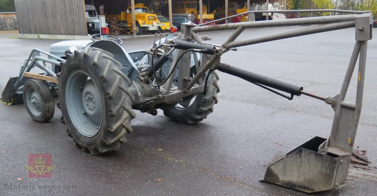 Ferguson TEA20. Grå traktor med lasteapparat foran og graveaggregat bak. Motoren er en 4-sylindret bensinmotor fra Standard Motor Company.