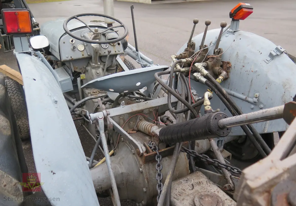 Ferguson TEA20. Grå traktor med lasteapparat foran og graveaggregat bak. Motoren er en 4-sylindret bensinmotor fra Standard Motor Company.