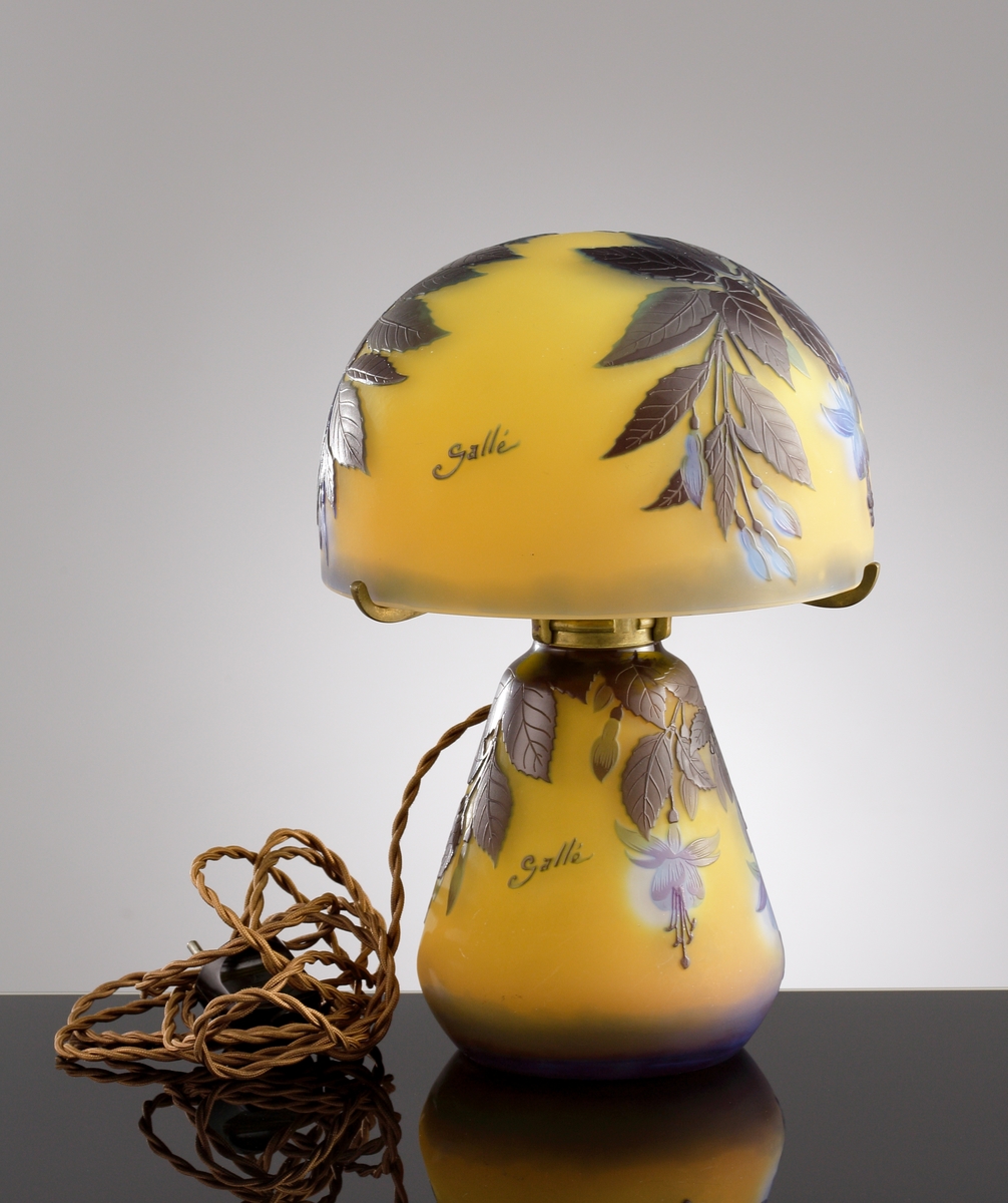 Gul opak lampa med växtmotiv. Etsat överfång i blått och gråbrunt.
Metallfattning för glödlampa. Tvinnad textilsladd.