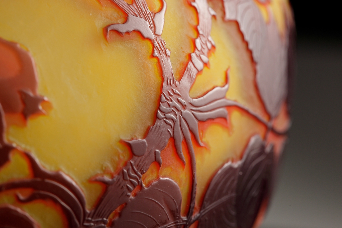 Lampa i skiftande gult, opakt glas. Dekor i rödbrunt etsat överfång. Motivet föreställer nyponkvistar.
Metallfattning för glödlampa. Tvinnad textilsladd.
Etikett: Skadad men "GALLÉ PARIS" kan uttydas.