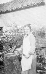 Tenestejente i arbeidsklær høgg ved. Det er Åsta Helene Sola