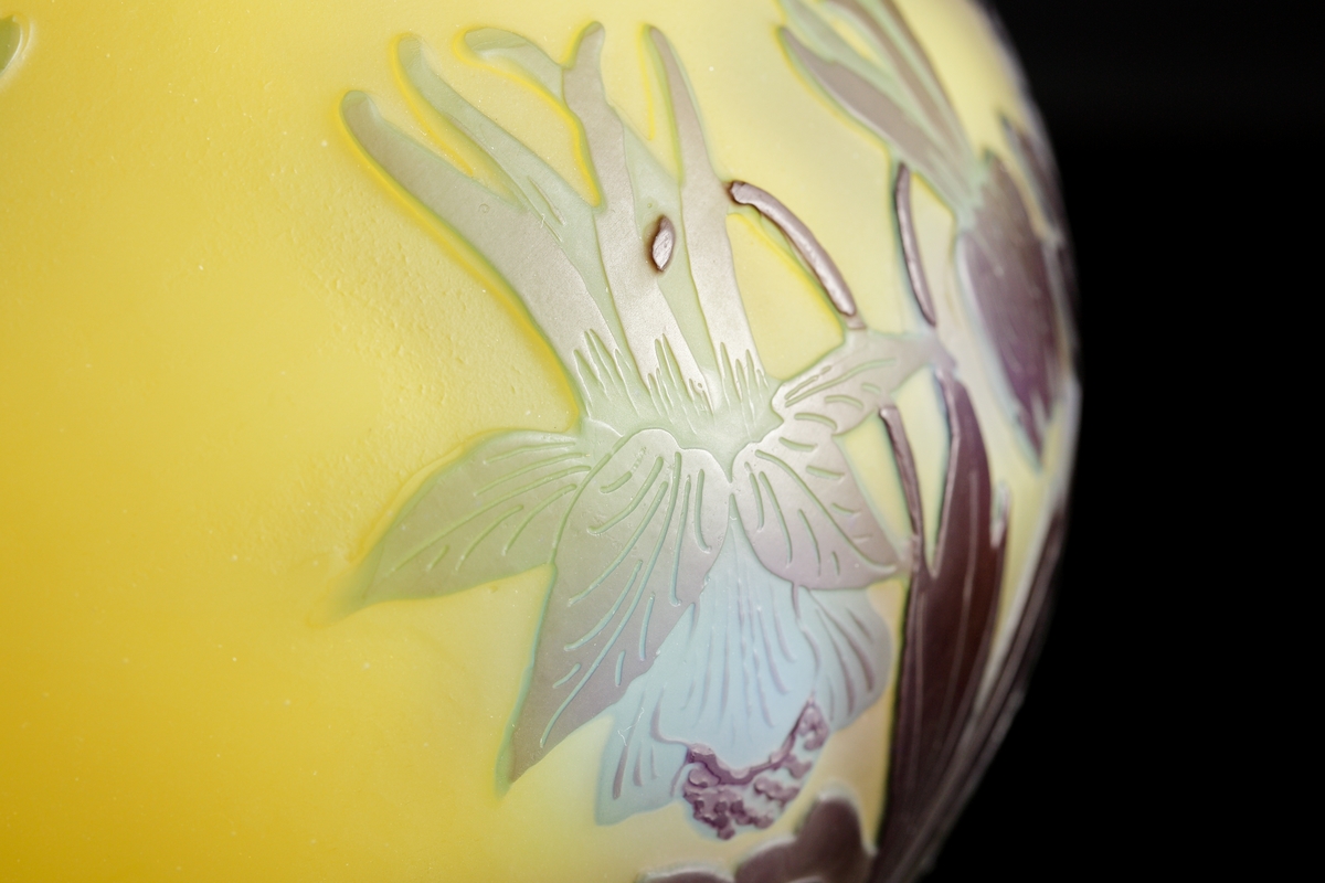 Halvopak, gul vas med etsat överfång i blå- och grönblå nyanser. Växtmotiv med blommor och blad.