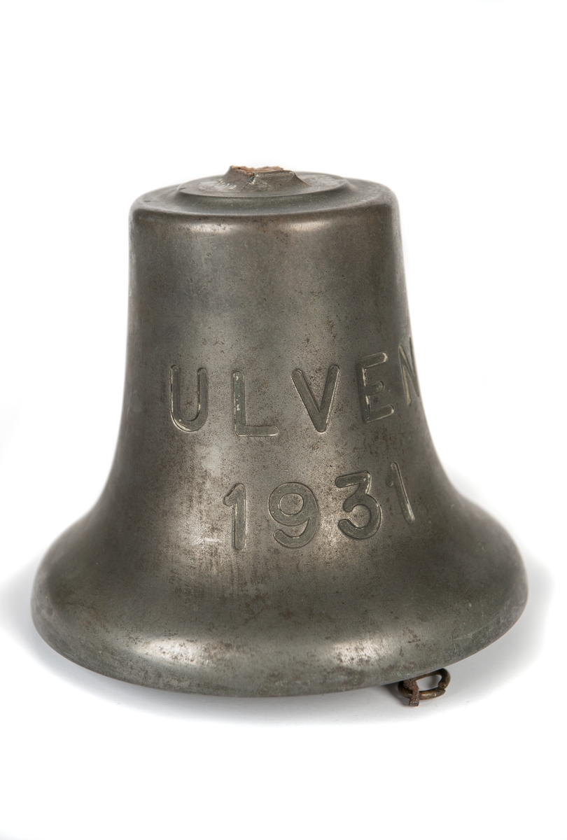 Skeppsklocka av malm med kläpp av järn. Ingraverat "ULVEN 1931". Upphängningsbygeln avslagen. Har tillhört ubåten ULVEN.