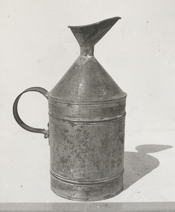 Fotogenkanna, "påfyllningskanna", av järnbleck. Cylindrisk form, med konisk överdel, påfyllningsöppning med trattformig avhällningsläpp. Handtag placerat på den cylindriska sidan, utan bärbygel. Rymd ca 5,5 l.