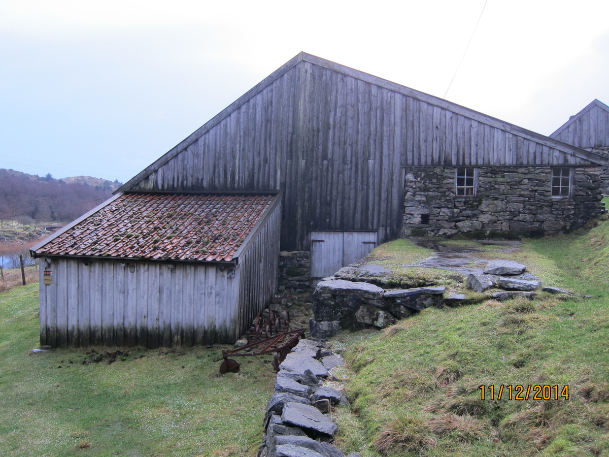Stavløe med sval. Fjøset er et tilbygg i tørrmur av naturstein.
