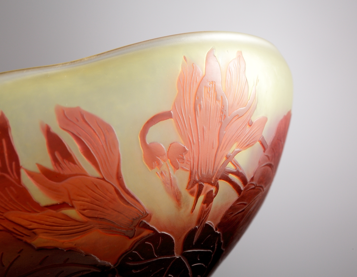 Halvopak gulvit skål med matt yta på utsidan, och blank på insidan. Etsat överfång i röda nyanser. Dekoren återger ett växtmotiv med blommor och blad.