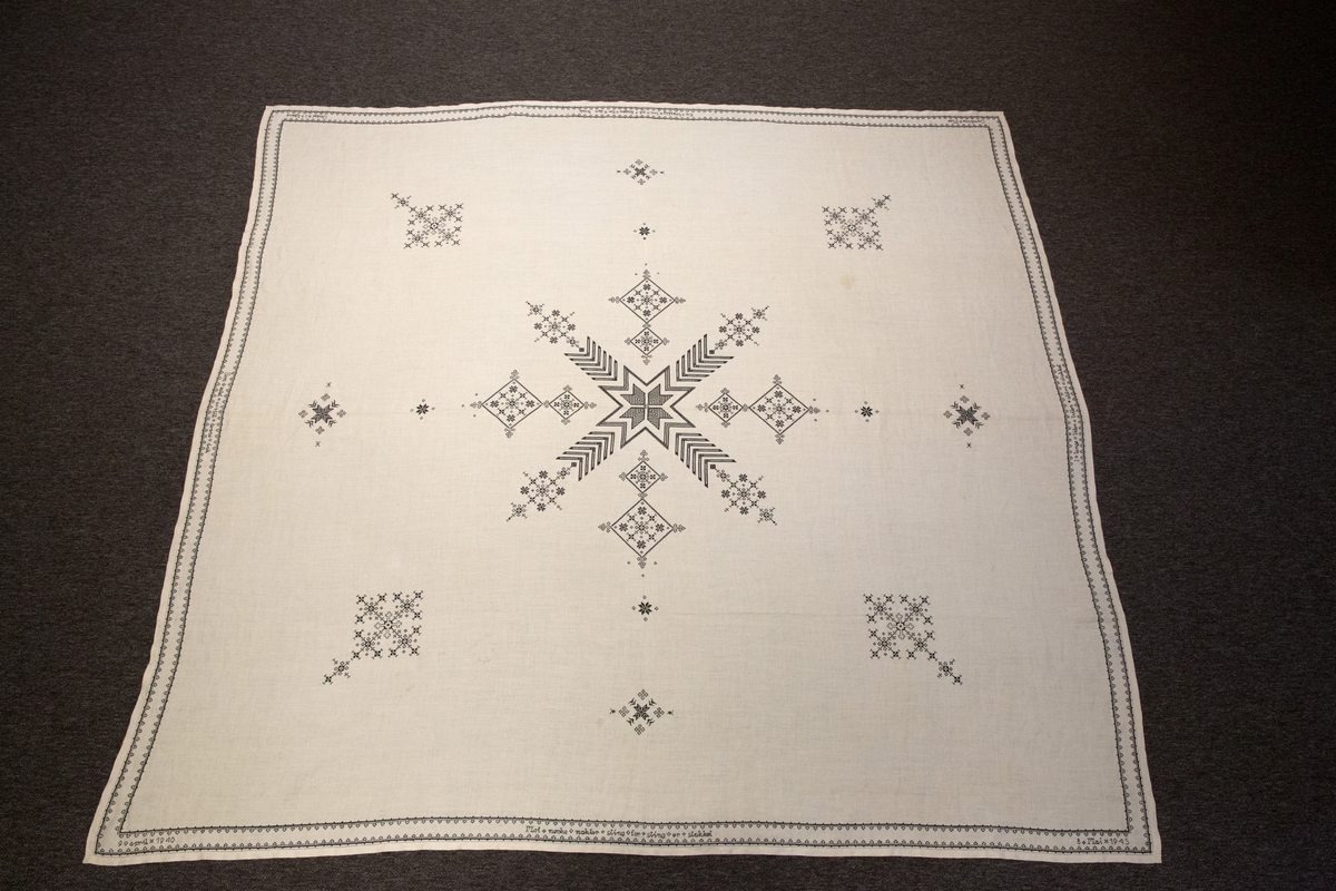 Brodert mønster og bokstaver. Tekst. 

Om symbolikken: Borden med motsatte kors skal symbolisere falne på begge sider under krigen. Her fins referanser til Maginotlinjen og slagene ved Pantelaria, Lampedusa og Midway. Langs kanten rundt er det bodert inn verslinjer.