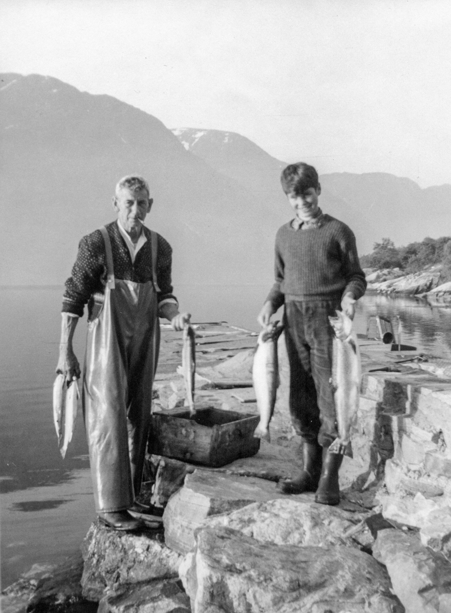 Mann og gut på fiske i fjorden.
