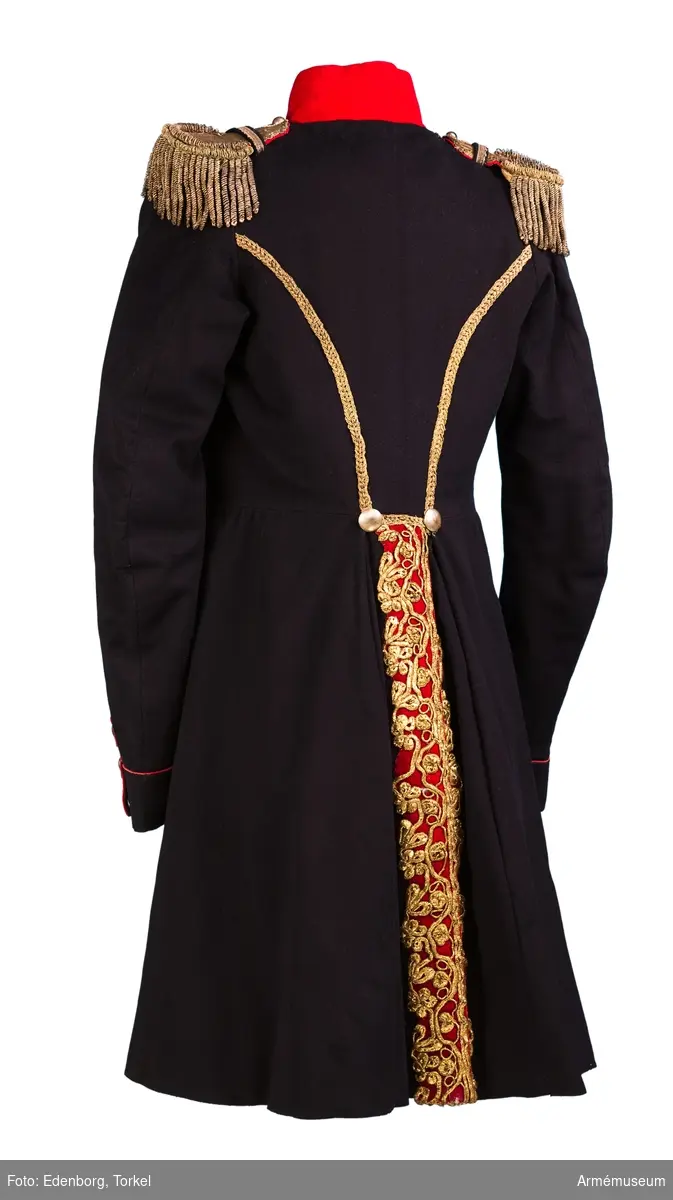 Blå knälång rock med röd krage och snörmakerier av förgylld metalltråd.
Renoverad och försedd med nya ärmuppslag omkring 1831.

Rocken är sydd av fint mörkblått kläde och har snörmakerier av guldlan fastsydda på en remsa av rött kläde på båda sidor om knäppningen mitt fram, samt i slitsen bak. Dessutom revärer över bröstet utförda av förgyllda tvinnade metallsnoddar, och 5 rader med 8 rent dekorativa knappar i varje rad. Knapparna är släta och svagt välvda, och av en försilvrad kopparlegering. Den egentliga knäppningen är 2 x 7 hyskor och hakar kant i kant mitt fram, samt 2 x 2 dito i kragen.
Rocken är konstruerad med fram- och sidstycken i ett, samt helt bakstycke utan söm mitt bak. Den har midjesöm med separat skört. Skörtet har fram- och sidstycken i ett, och två smalare bakstycken vid slitsen bak. Röd ståndkrage av fint kläde, fodrad med det samma.
Ärmarna är formade tvåsömsärmar med fasta ärmuppslag med smal röd passpoal och röd matta med tre "knapphål" av metallgalon som pryds av tre mindre knappar.
De svängda sidsömmarna bak är dekorerade med samma förgyllda tvinnade metallsnoddar som revärerna. Vid ryggslutet sitter två knappar.
Bålen är fodrad med gråvitt fint ylletyg, medan ärmarna är fodrade med oblekt eller vitt linne.

Till rocken hör ett par epåletter av silvergalon med fransar av krusade och vridna silvertrådar.