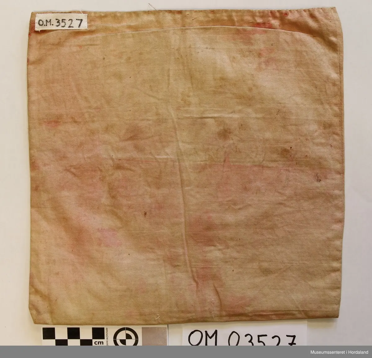 Form: rektangulær, ikkje kant oppe, men det er merke etter kant. Broderi sydd på stramei. Svart botn, påsydde perler i liljemotiv. Rosa, dobbelt bakstykke. Nedom det svarte broderiet er det ein svart brodert kant med initialer i lilla.