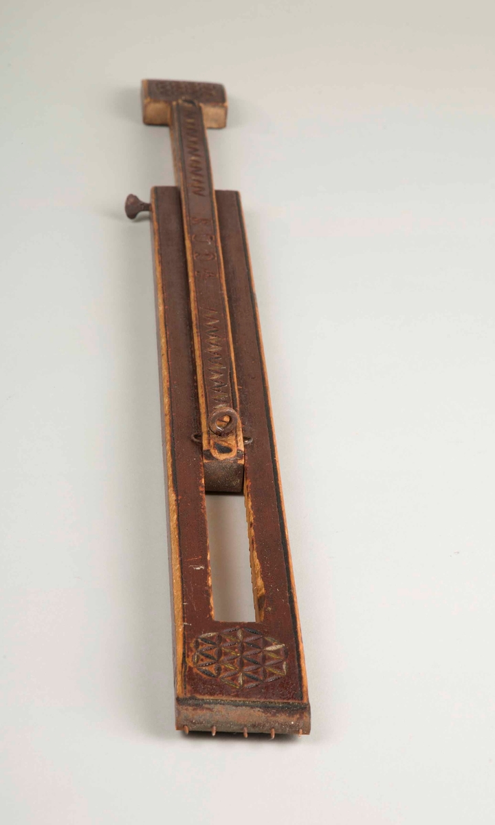 En rødbrun avlang spenne i tre som kan trekkes ut