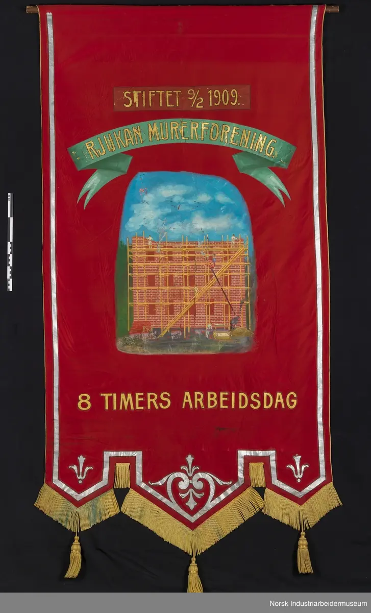 Side 1: Bygg som mures opp, stillas, arbeidere, blå himmel bak. Sølvbånd langs kantene.
Side 2. Sølvornament og sølvbånd langs kantene.